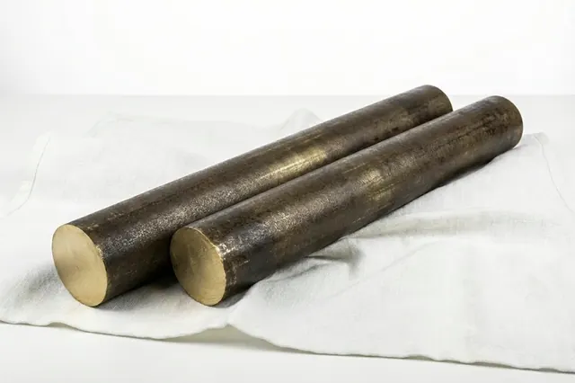 Two bronze rods with turned surface laid on a white cloth